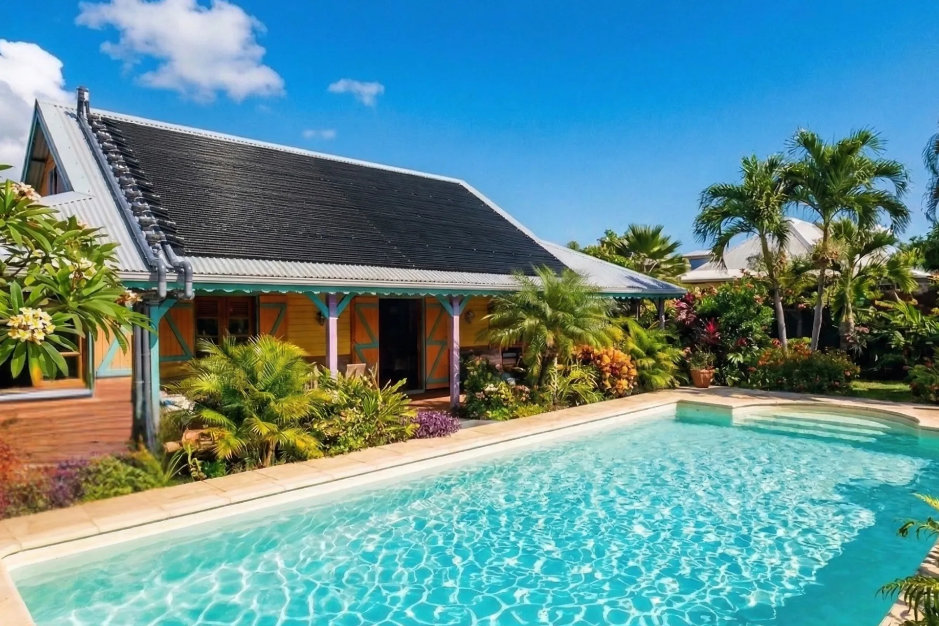 Piscine tropicale chauffée au solaire avec maison créole et palmiers à la Réunion